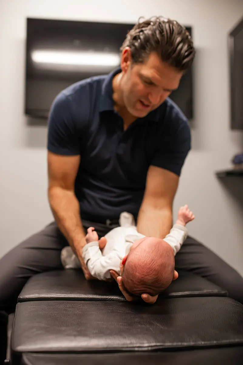 Dr. Justin Berlin Performing Chiropractic Adjustment on Infant at Delta Chiropractic in Rochester Hills, MI